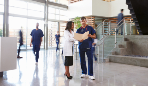 Two,Healthcare,Workers,Talk,In,The,Lobby,Of,A,Busy